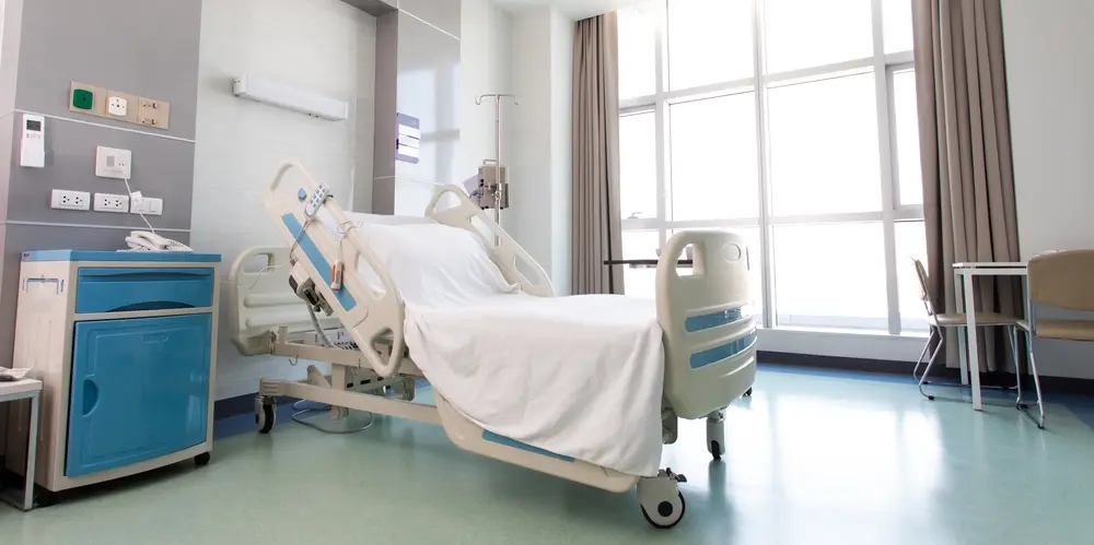 A clean hospital room with a ready bed.